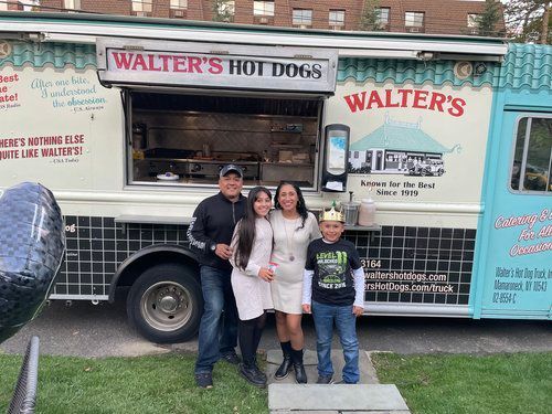A family is standing in front of a food truck.