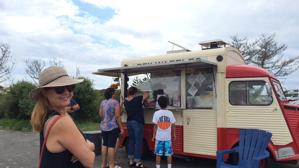 A group of people are standing in front of a food truck.