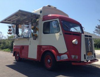 A red and white food truck is parked on the side of the road.