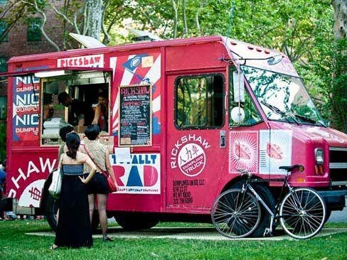 A food truck is parked on the side of the road in front of a building.