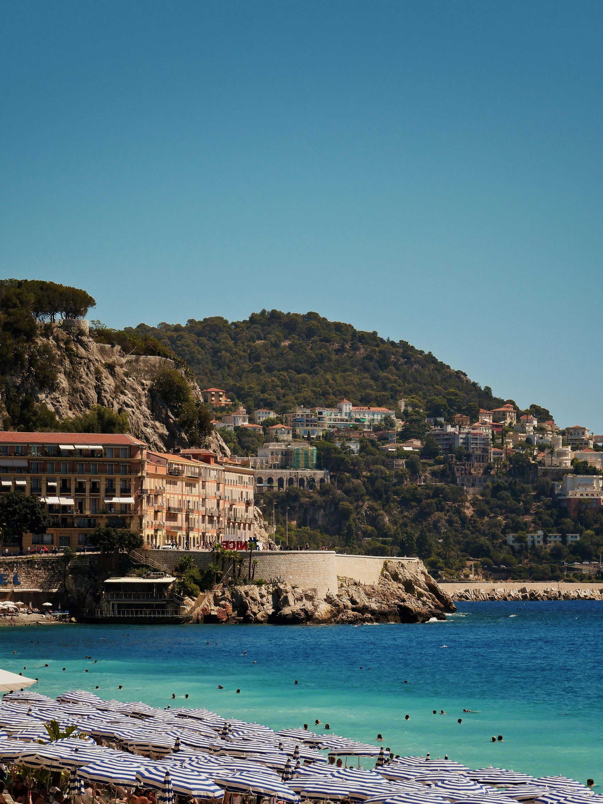 A beach with lots of umbrellas and a mountain in the background
