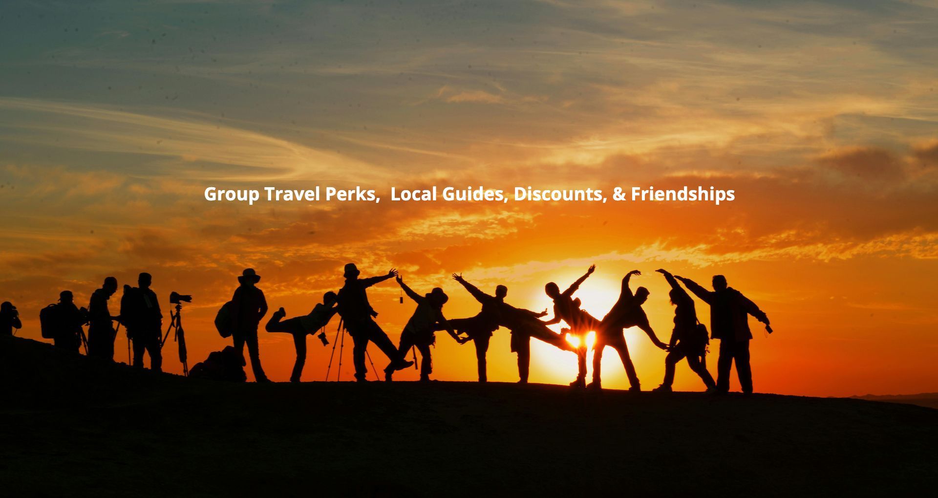 A group of people are standing in front of a sunset holding hands.