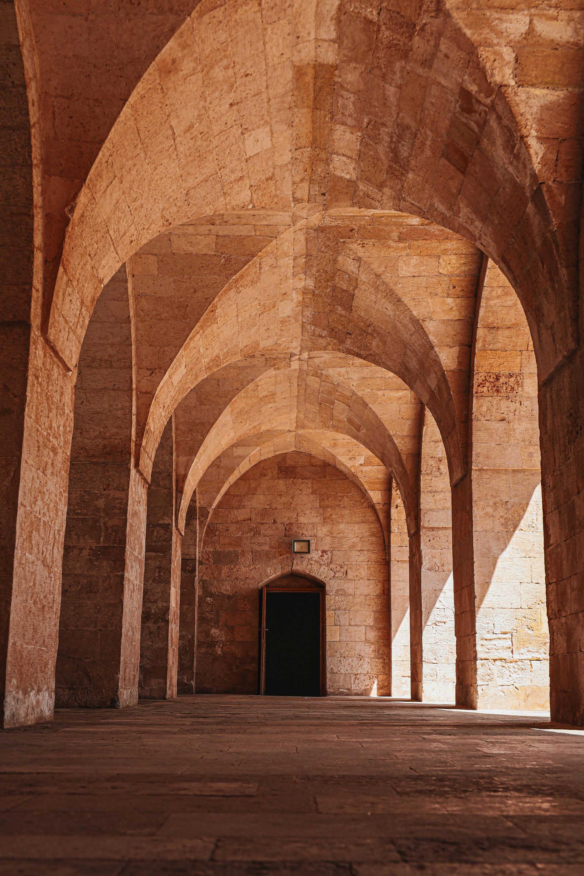 A long hallway with arches and columns in an old building.