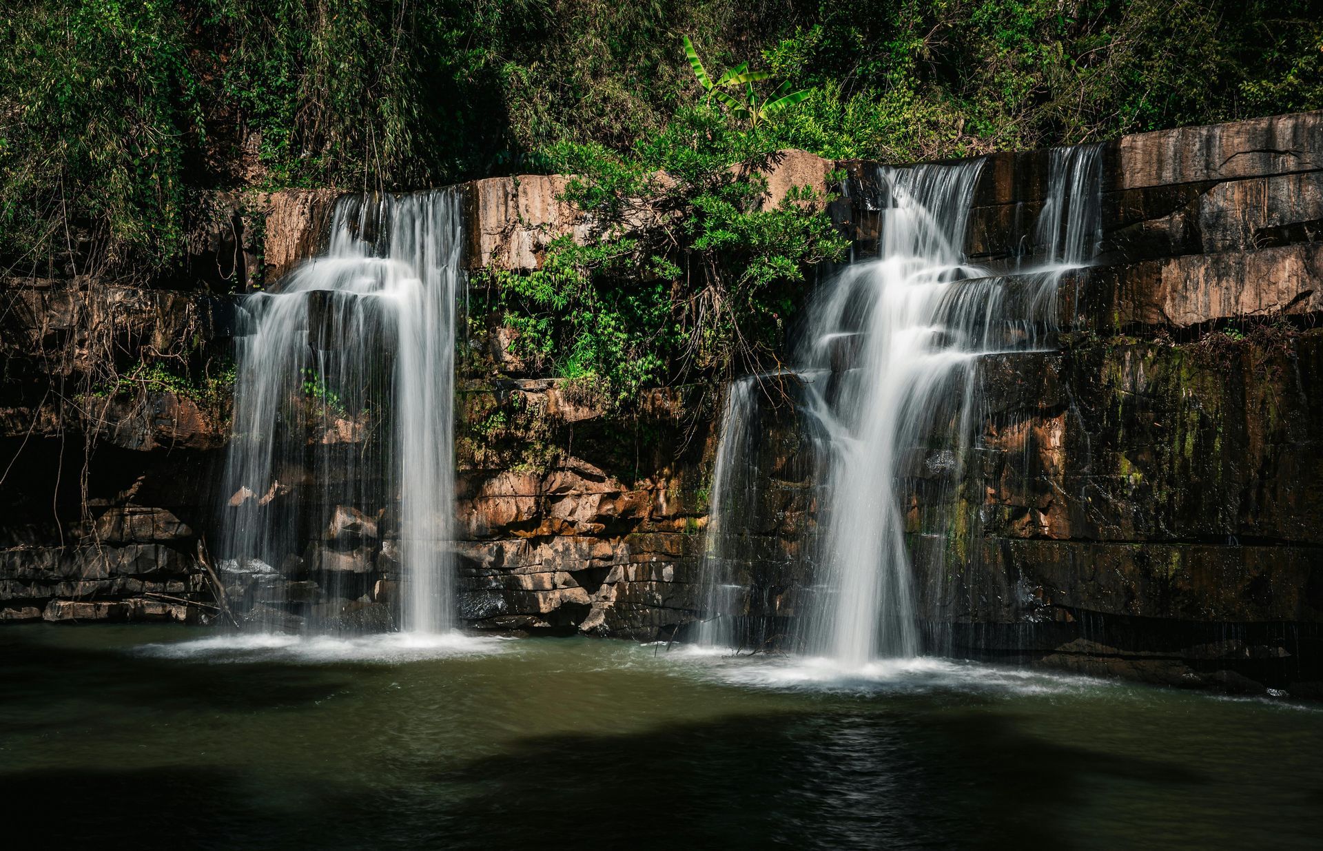 A waterfall is surrounded by trees and rocks in the middle of a forest.