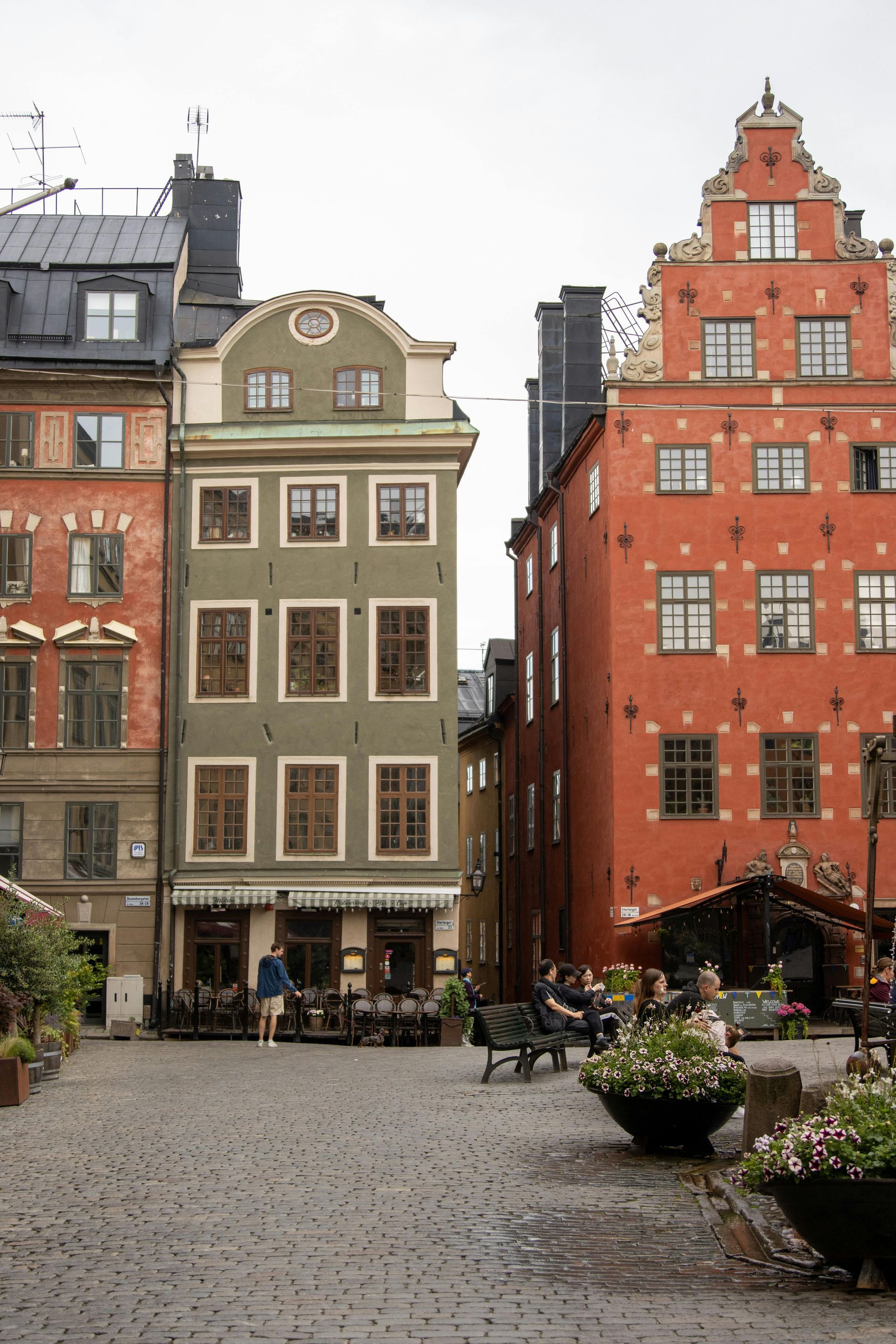 A group of people are walking in front of a row of buildings.