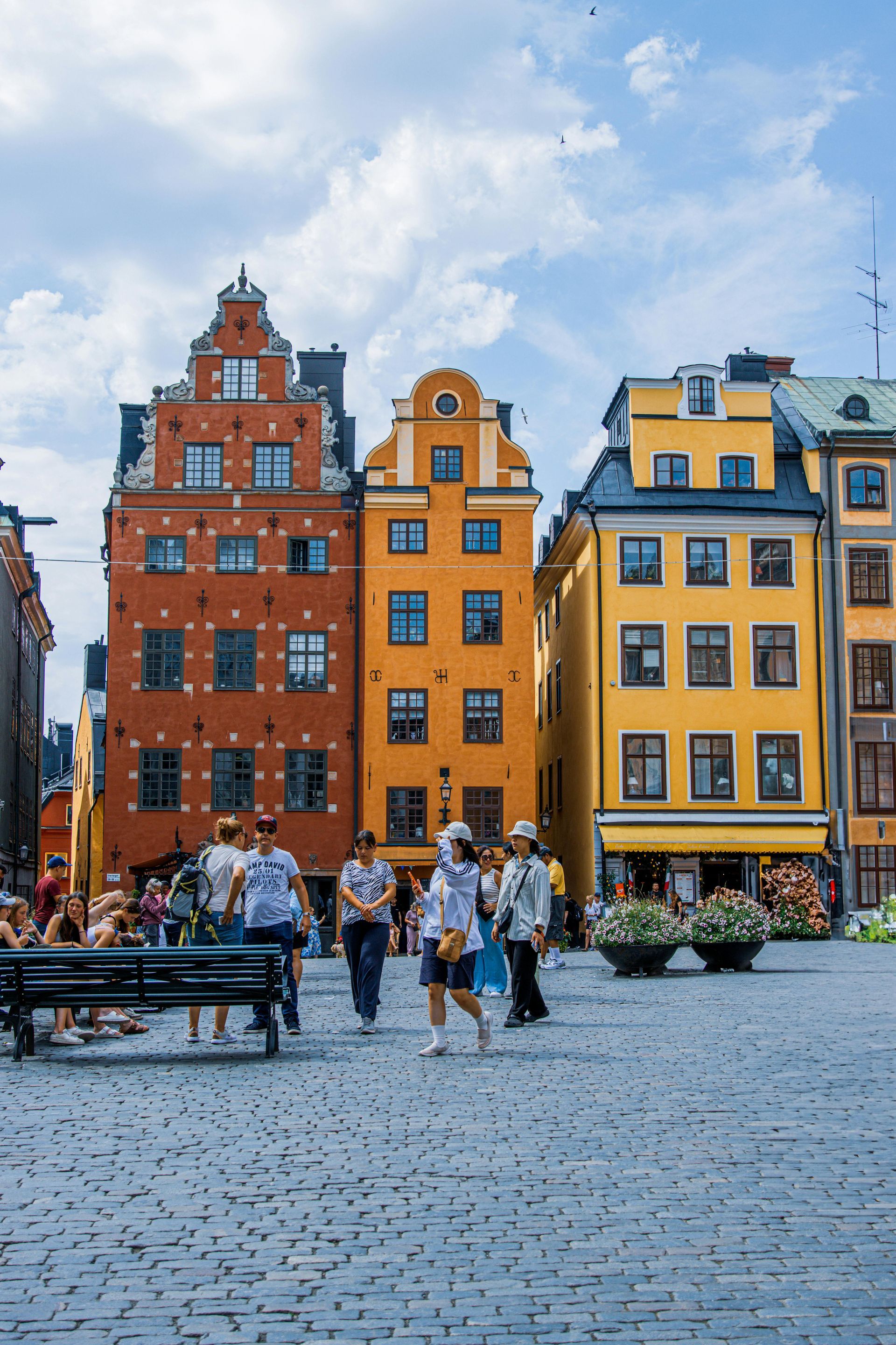 A group of people are walking in front of a row of buildings.