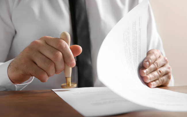 Hand stamping a document on a desk while holding pages aside