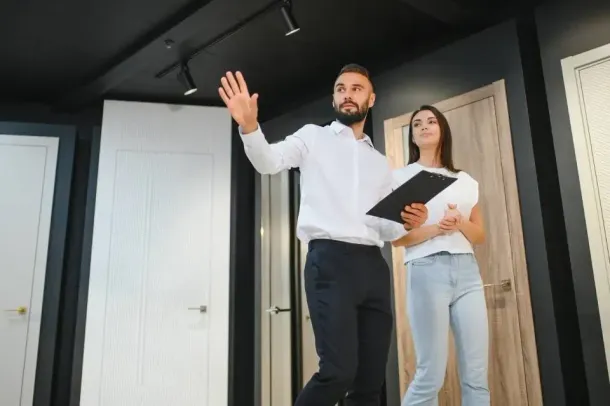 Real estate agent showing a modern apartment, holding a clipboard and gesturing toward the room