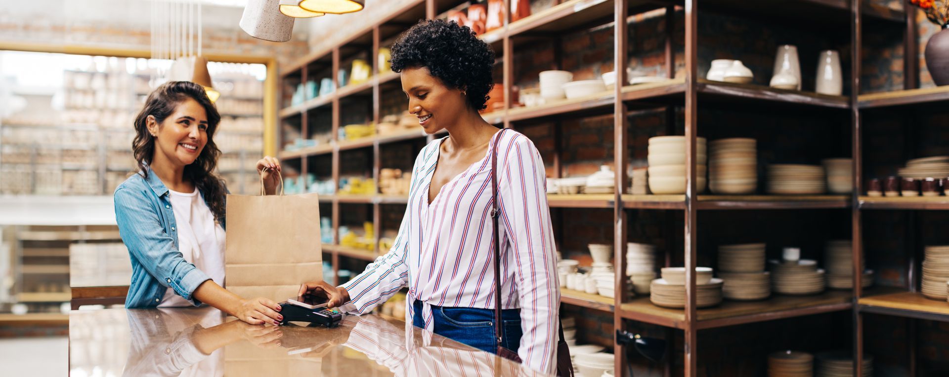 Two women are standing at a counter in a store.