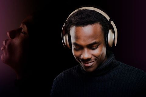 A man wearing headphones is smiling while listening to music.