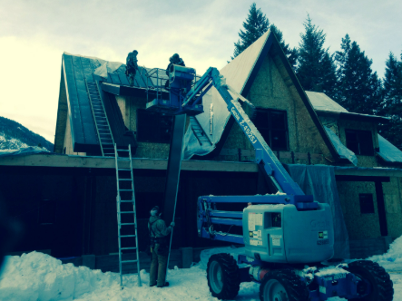 A man is standing on a ladder next to a crane that says genie on it.