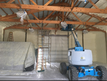 A blue and white tractor is parked inside of a building.