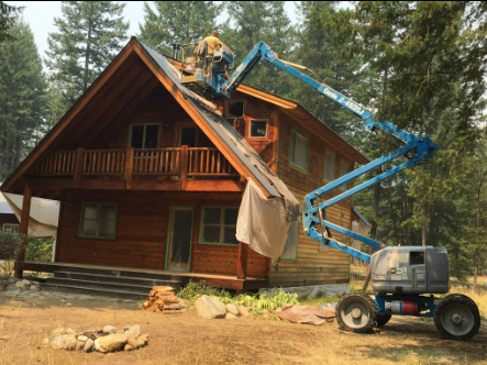 A man is working on the roof of a log cabin.