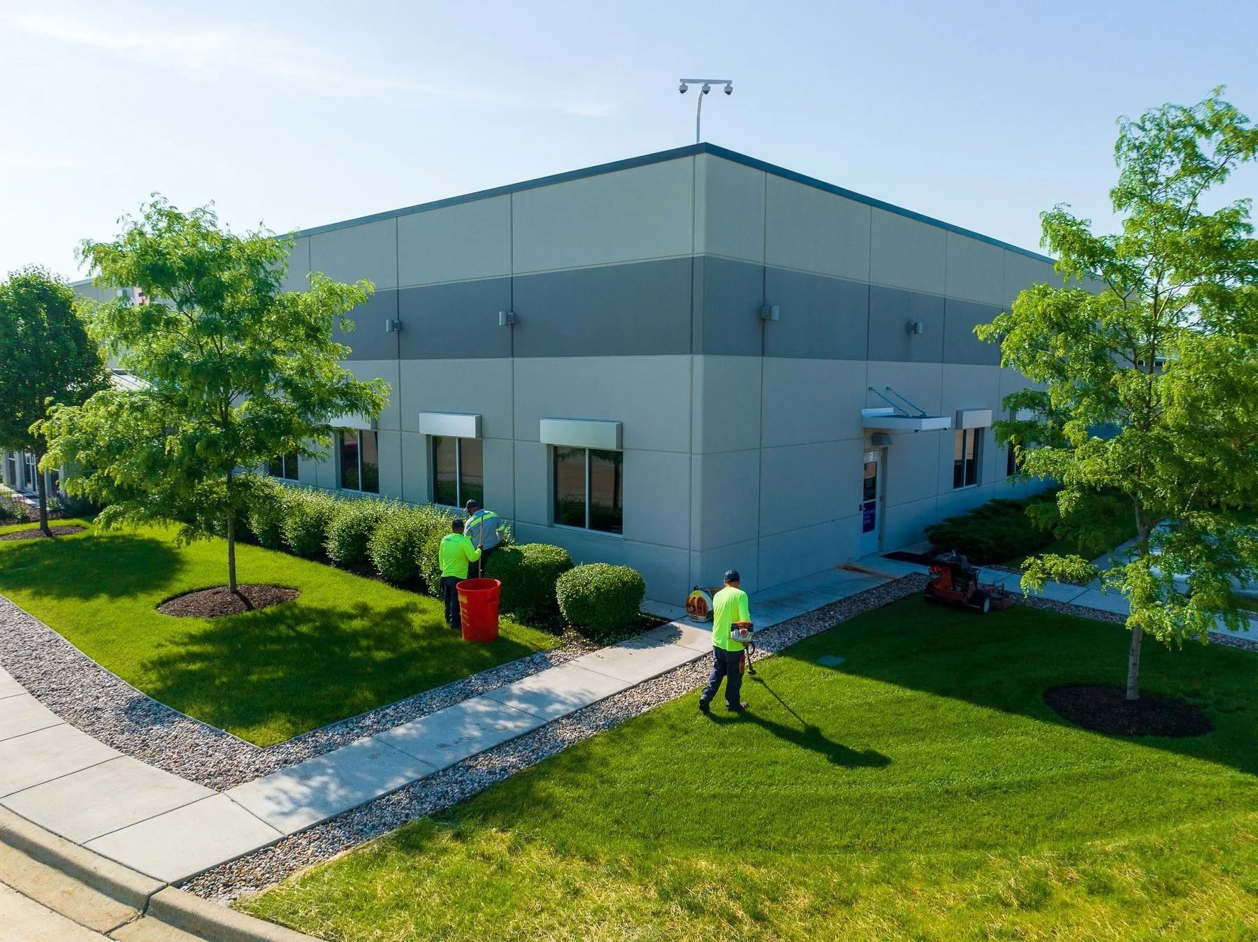 Modern industrial building with landscaping and two workers outside on a sunny day