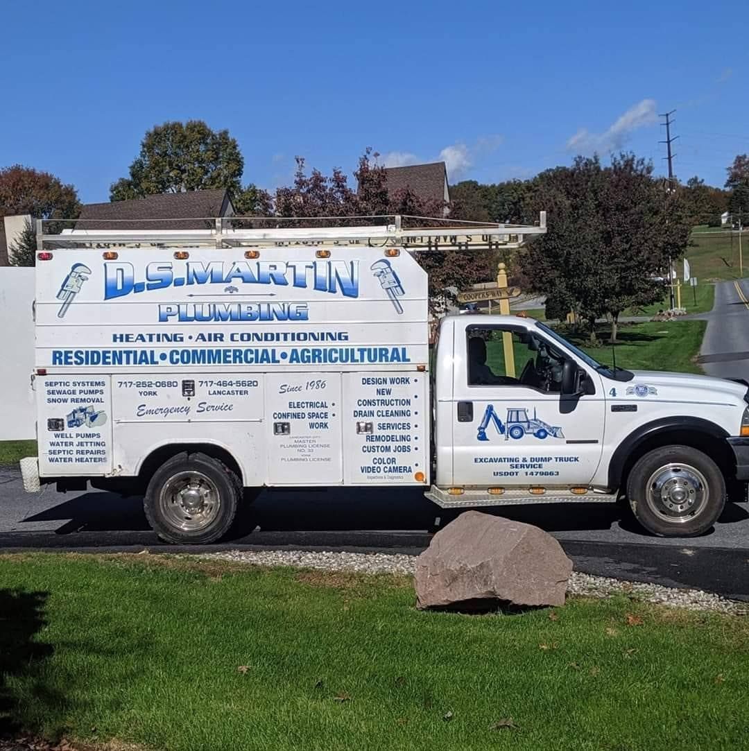 White plumbing service truck parked on grass, logo reads “D.J. Martin Plumbing”.
