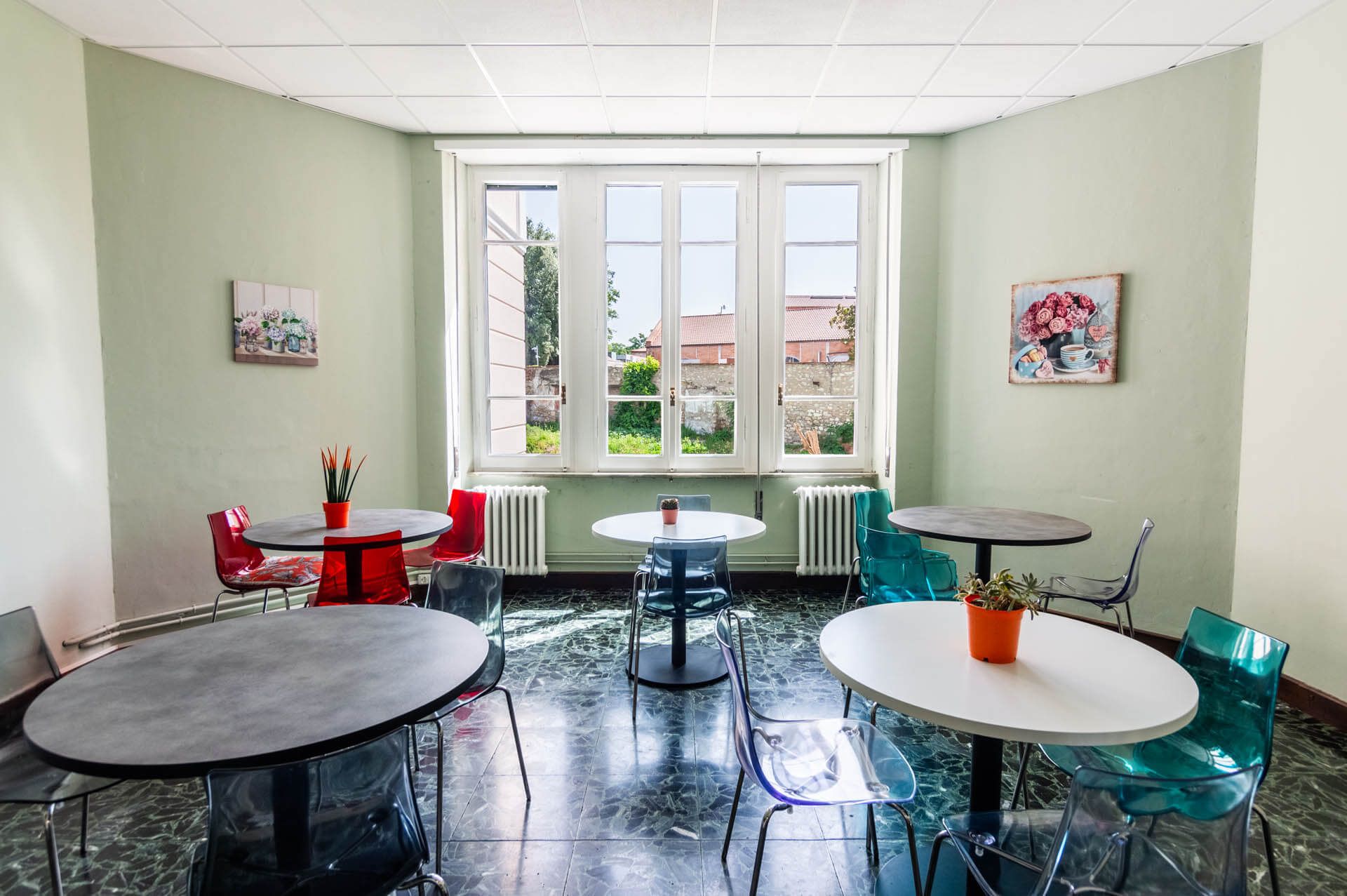 Una stanza con tavoli e sedie e una grande finestra.