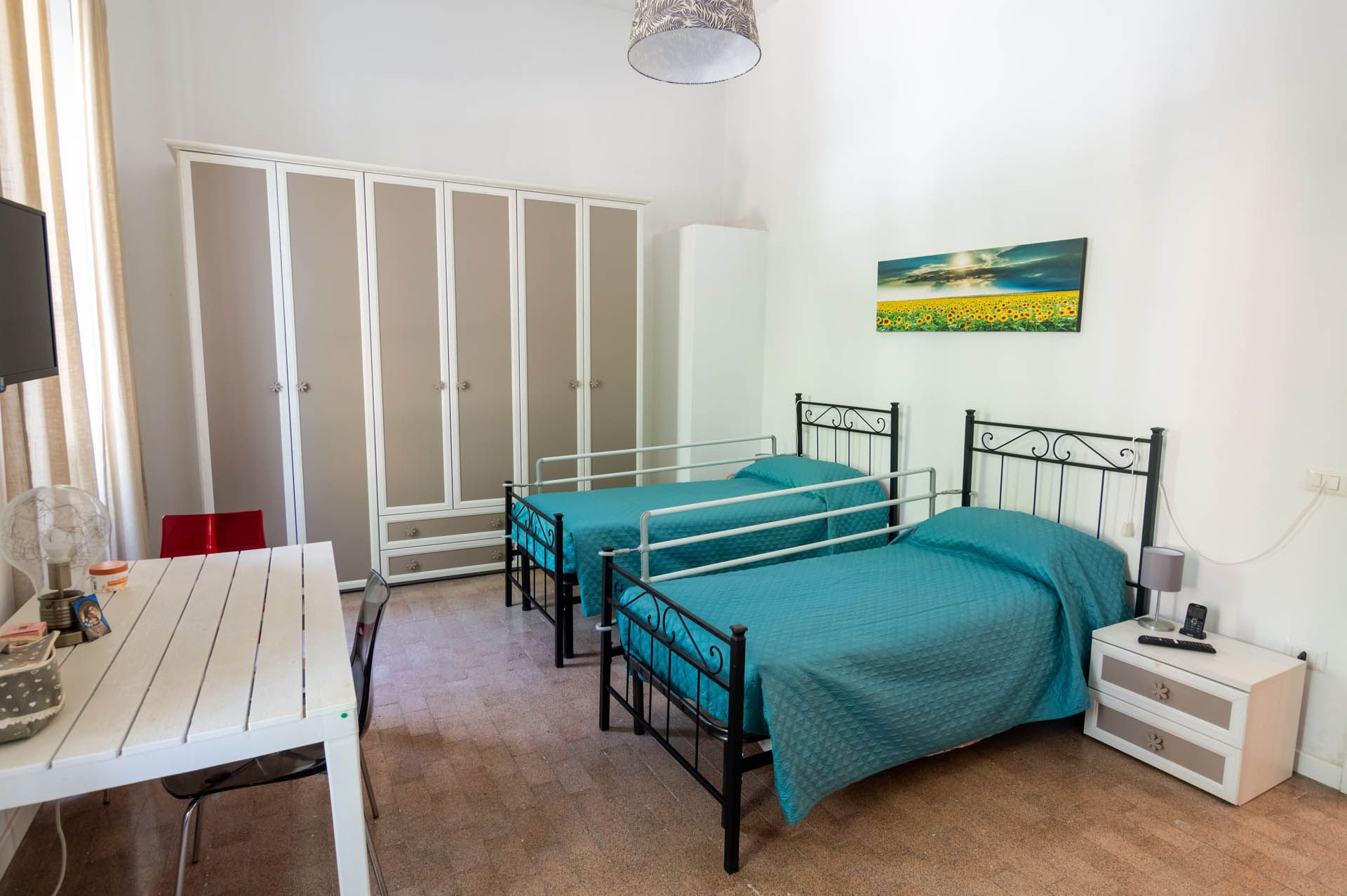 Una camera da letto con due letti, una scrivania e un quadro sul muro.