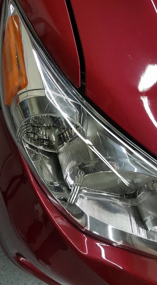 Close-up of a car's red fender and headlight. The headlight has a clear plastic cover, with an amber turn signal lens.