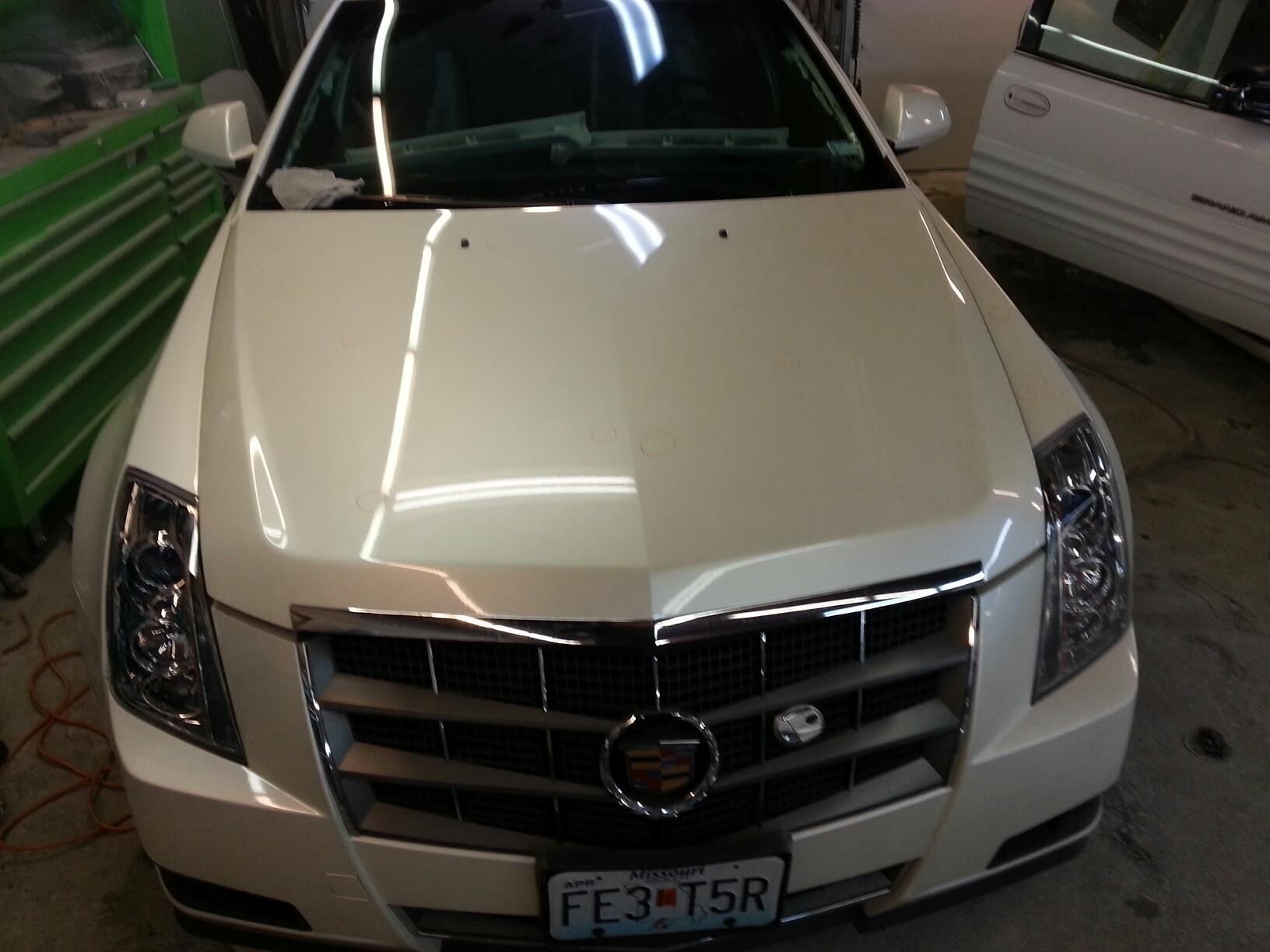 White Cadillac CTS in a garage, front view. Car has a chrome grill and license plate.
