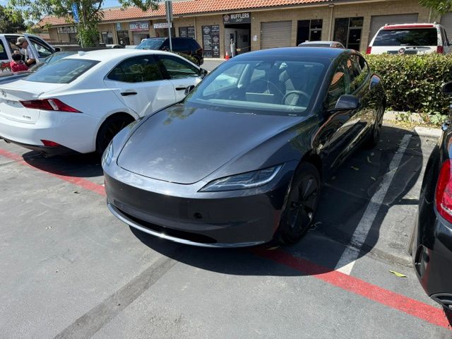 Dark gray Tesla parked in a lot next to a white car.
