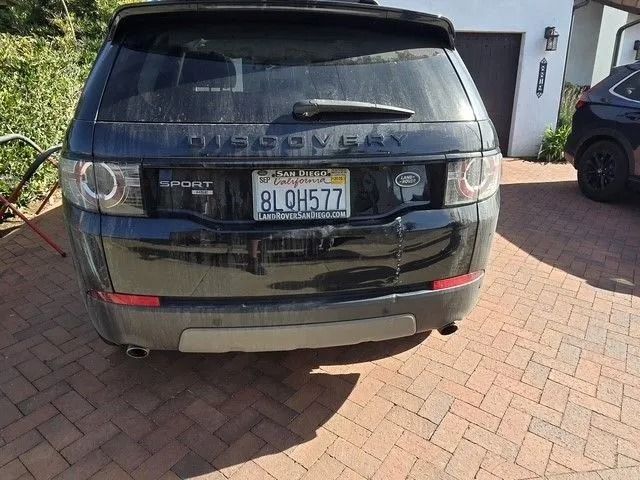 Black SUV being prepped for paint in a garage. Sections are covered in plastic and tape.