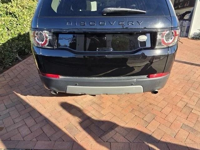 Black SUV, partially covered in plastic, in a garage. Front bumper appears freshly painted.