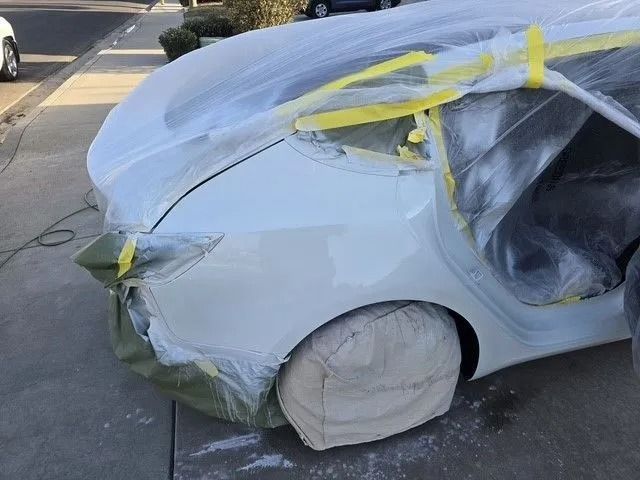 White Ram pickup truck parked on a driveway; a car is visible in the street in the background.