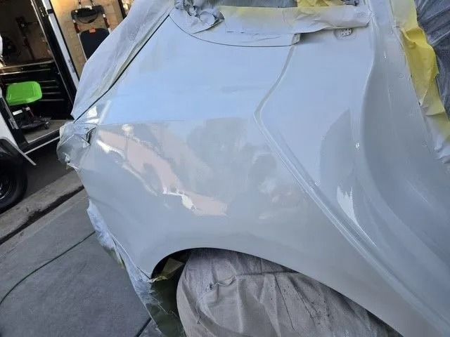 White pickup truck with a dent on the driver's side door. The truck is parked outdoors on a sunny day.