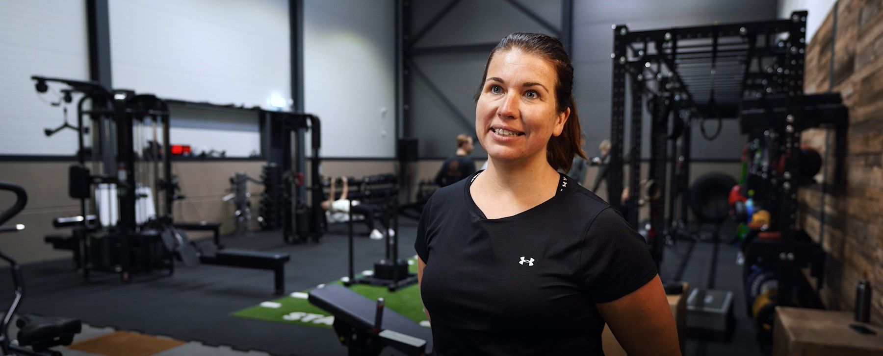 Kale man in grijs shirt in de sportschool, voor hometrainers met schermen.
