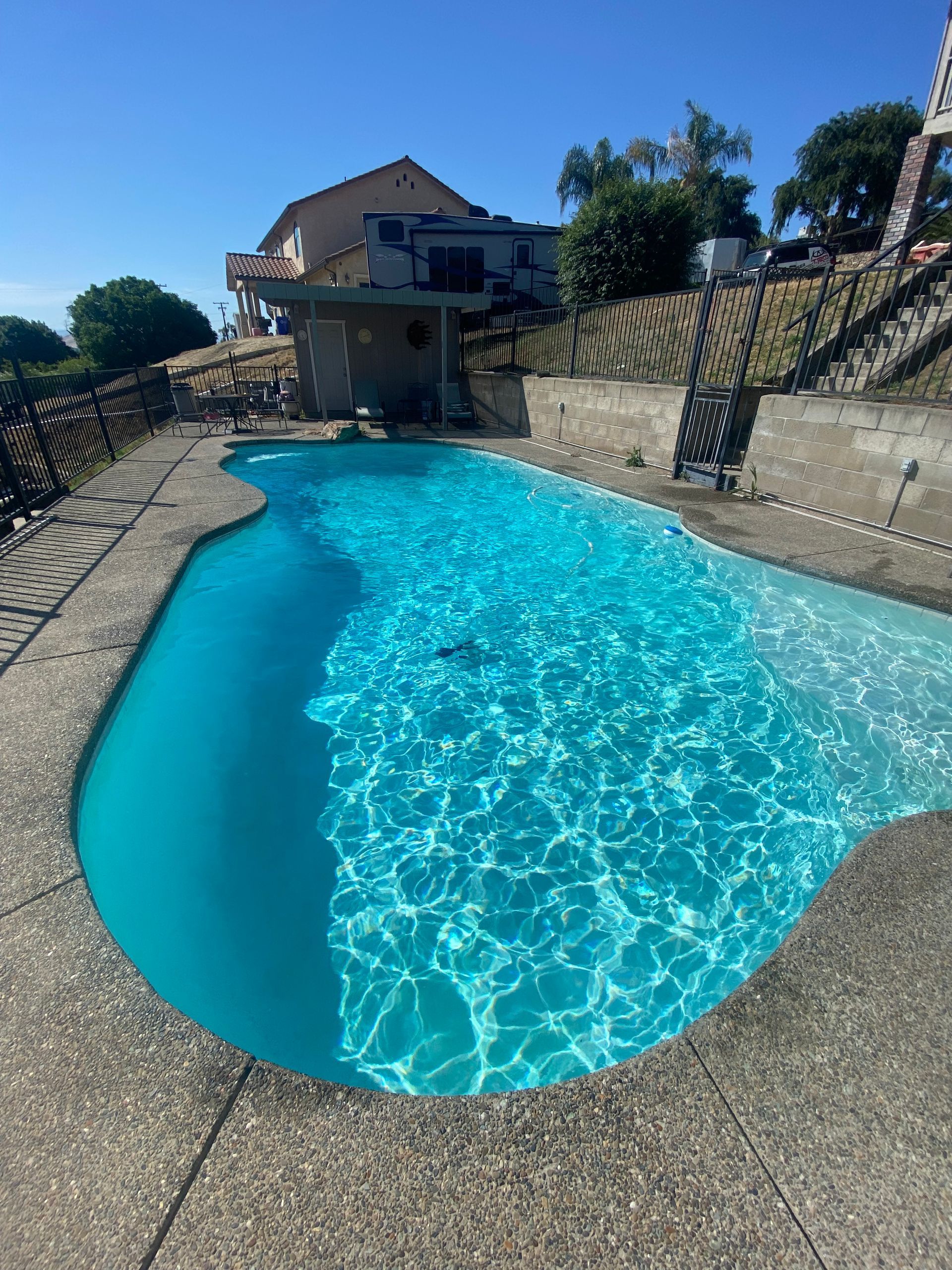 A large swimming pool with a house in the background