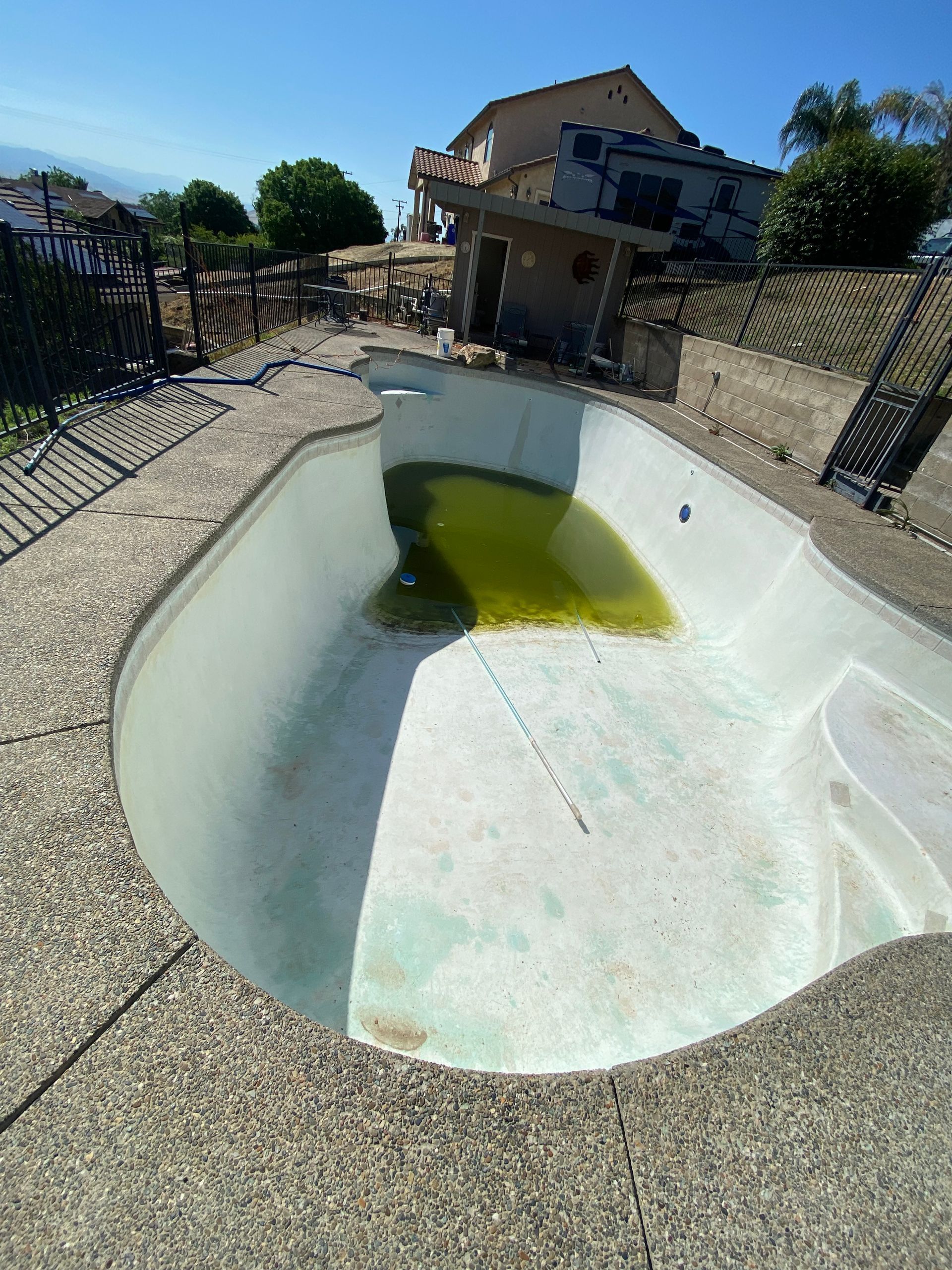 An empty swimming pool with a house in the background.