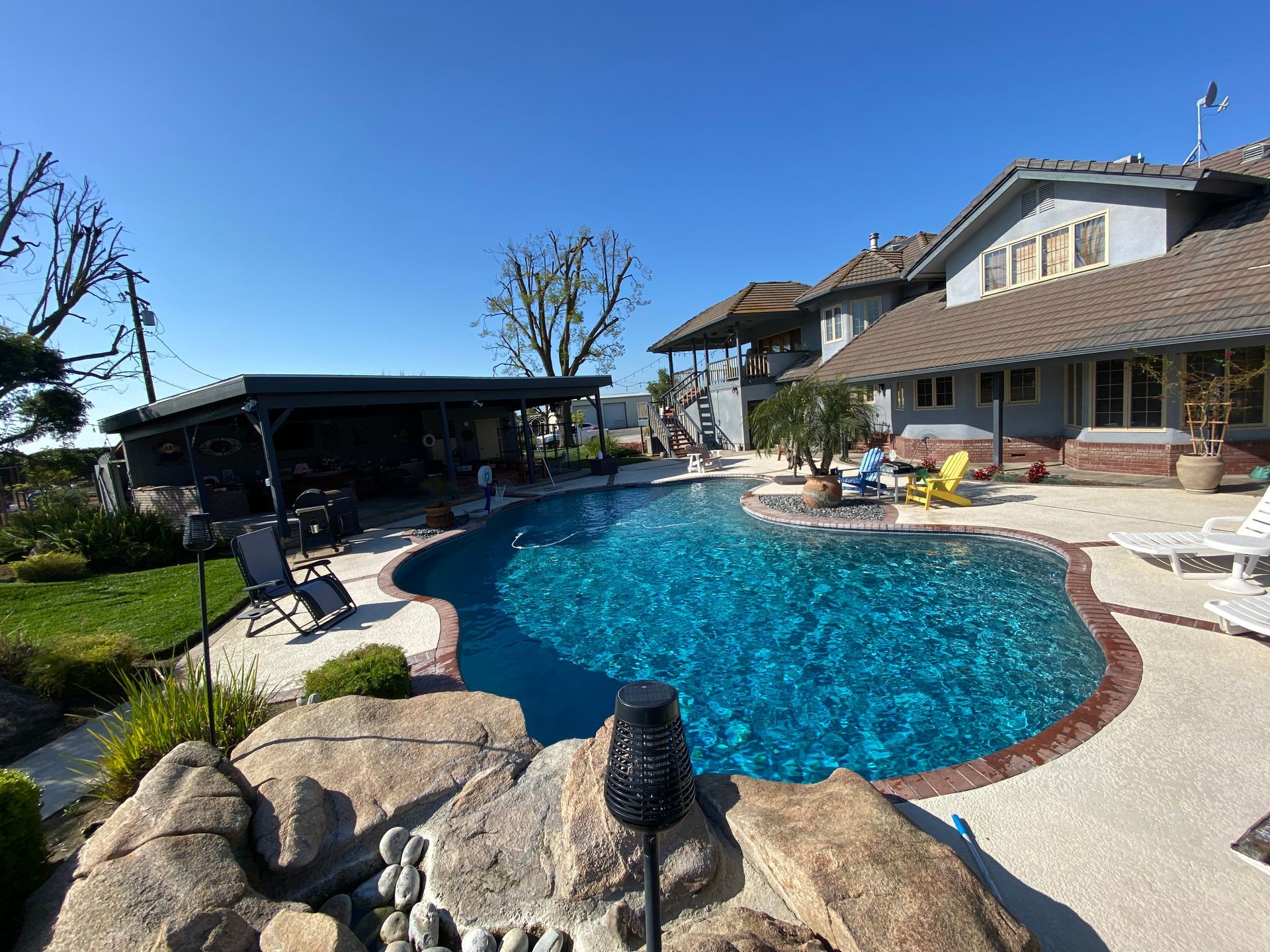 A large swimming pool is in the backyard of a house.
