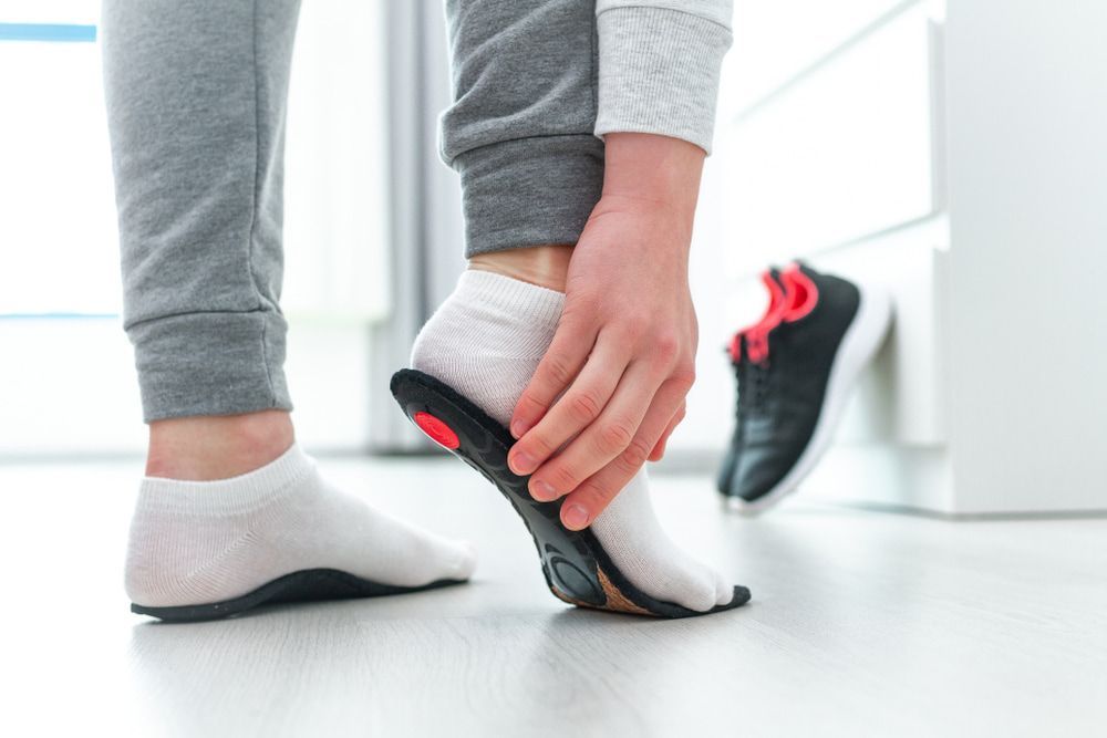 A Person Is Putting a Shoe Insole on Their Foot — Swan Podiatry and Orthotics in Coconut Grove, NT