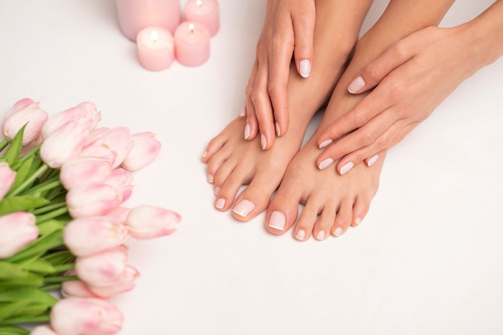 A Woman's Feet and Hands with Pink Nail Polish Next to A Bouquet — Swan Podiatry and Orthotics in Coconut Grove, NT