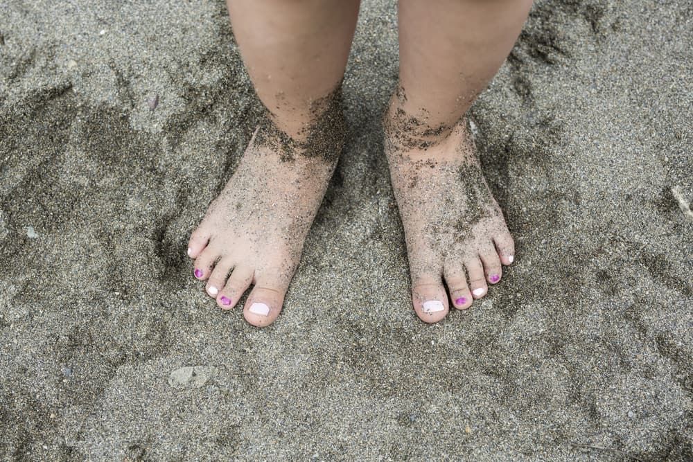 A Person 's Feet Are Covered in Sand on The Beach — Swan Podiatry and Orthotics in Coconut Grove, NT