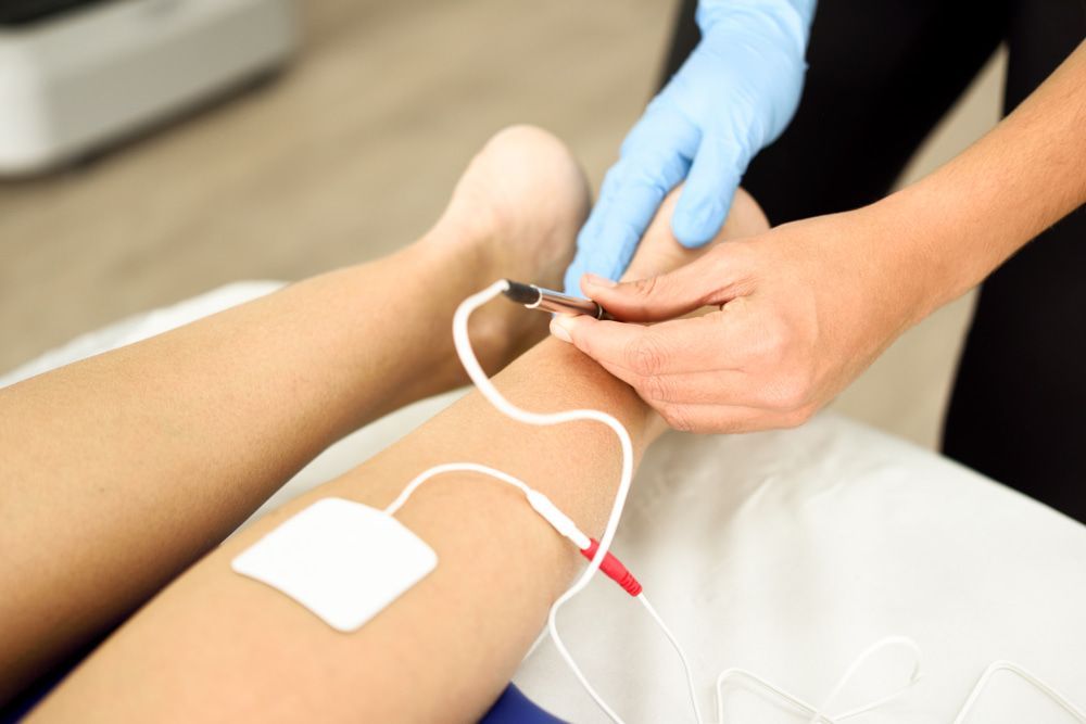 A Person Is Getting an Electrotherapy Treatment on Their Leg — Swan Podiatry and Orthotics in Coconut Grove, NT