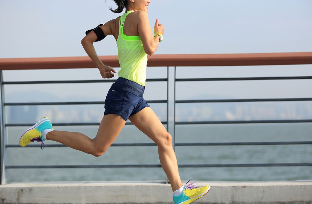 A Woman Is Running on A Bridge Near the Water — Swan Podiatry and Orthotics in Coconut Grove, NT