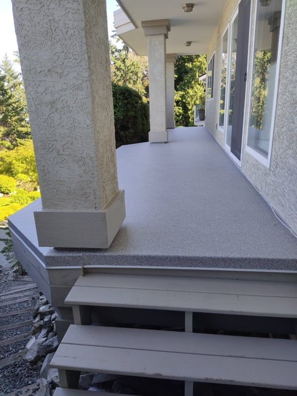 A porch with stairs and a concrete floor.