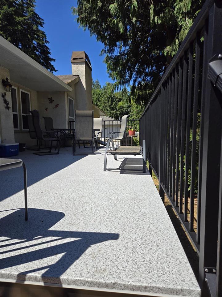 A deck with a black railing and chairs on it.