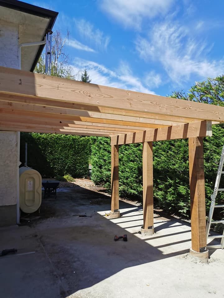 A wooden pergola is being built in front of a house.