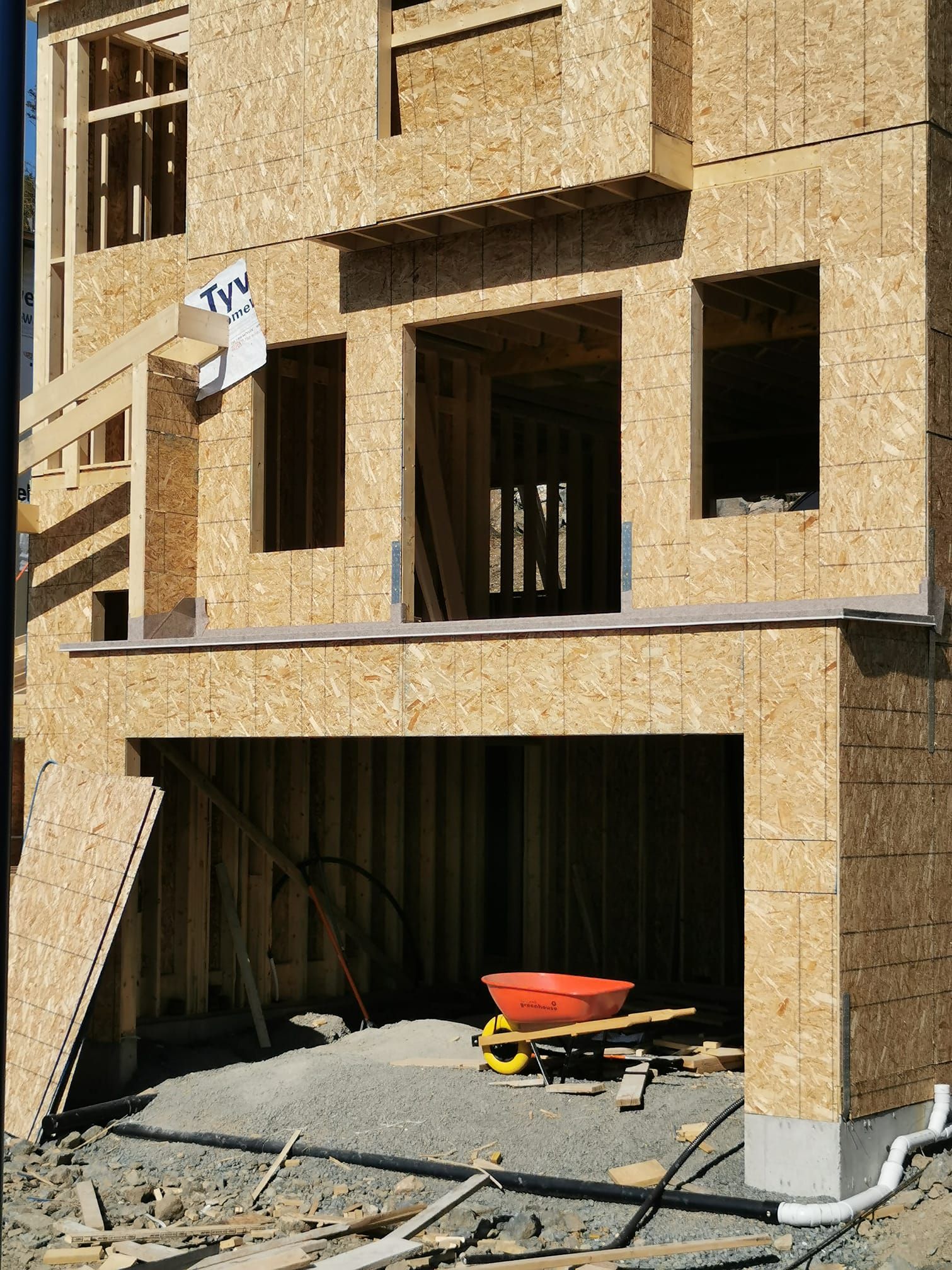 A building under construction with a wheelbarrow in front of it.