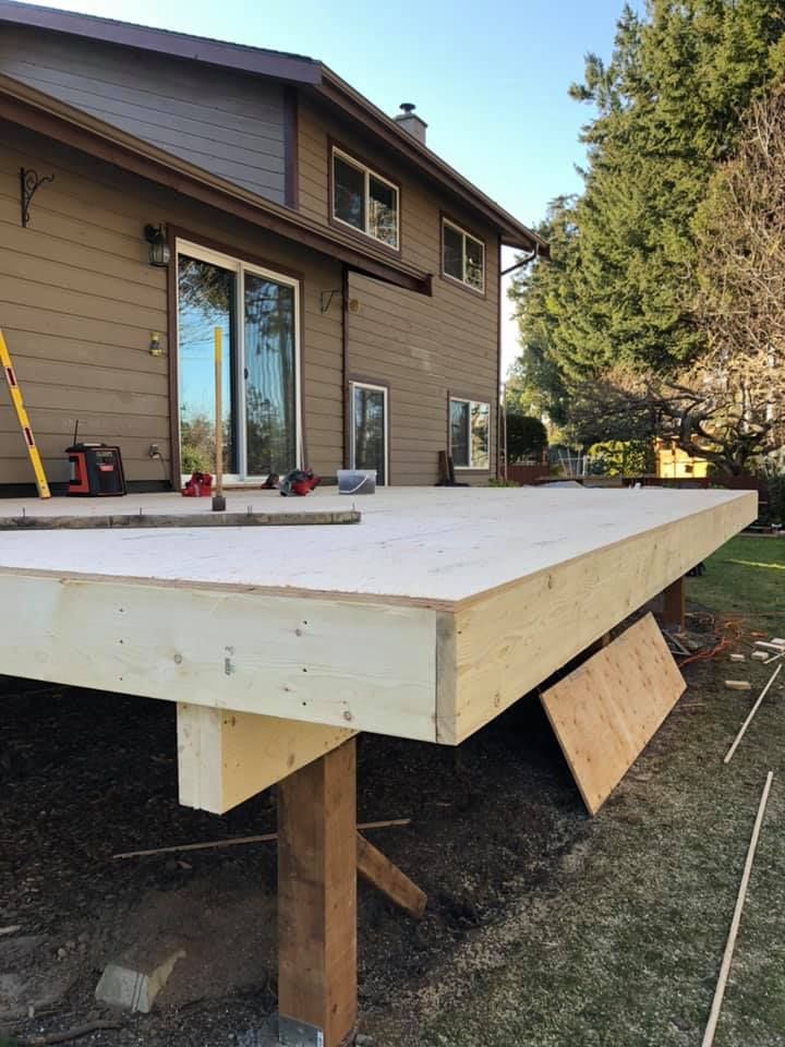 A wooden deck is being built in front of a house.