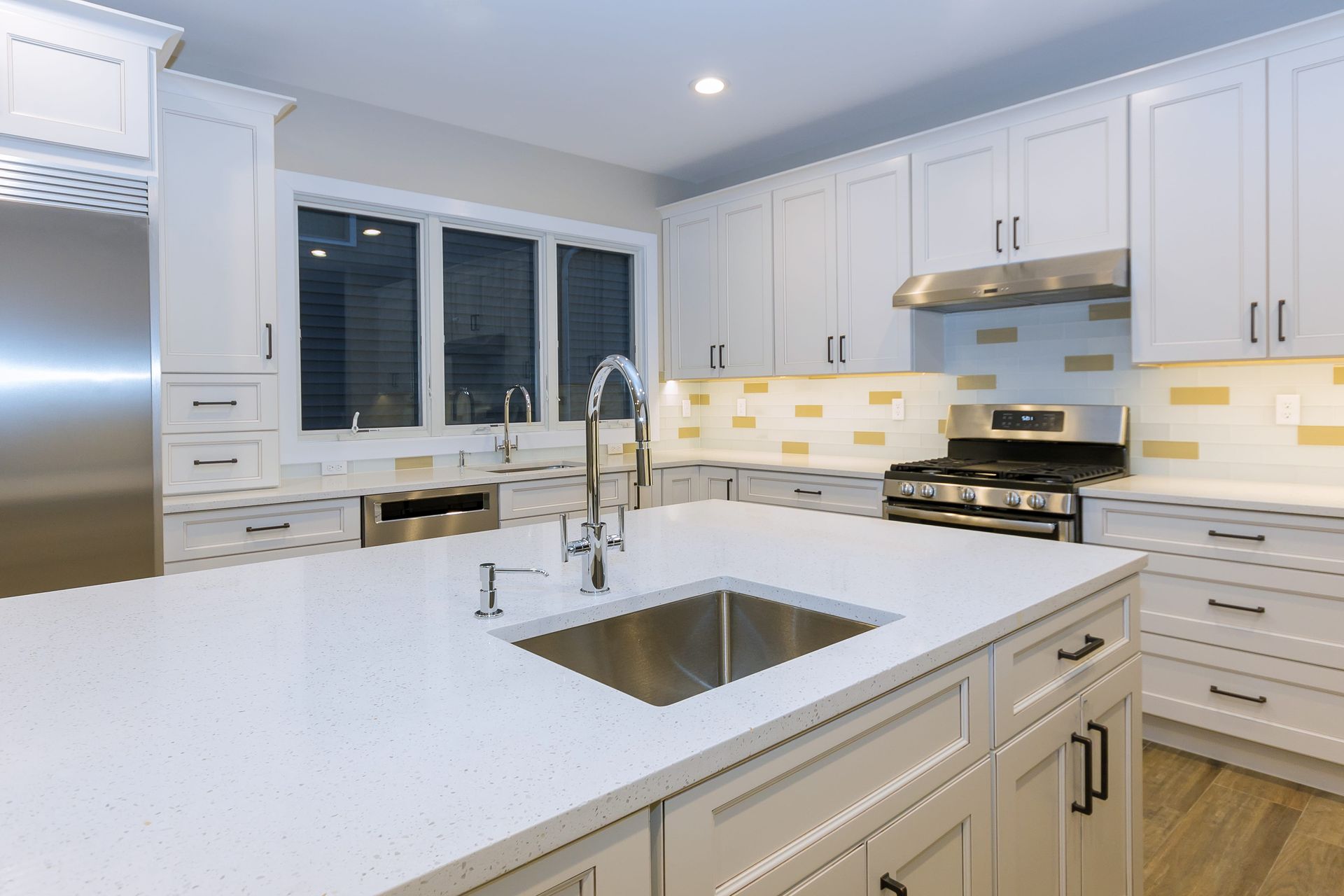 A kitchen with white cabinets, stainless steel appliances, and a sink.