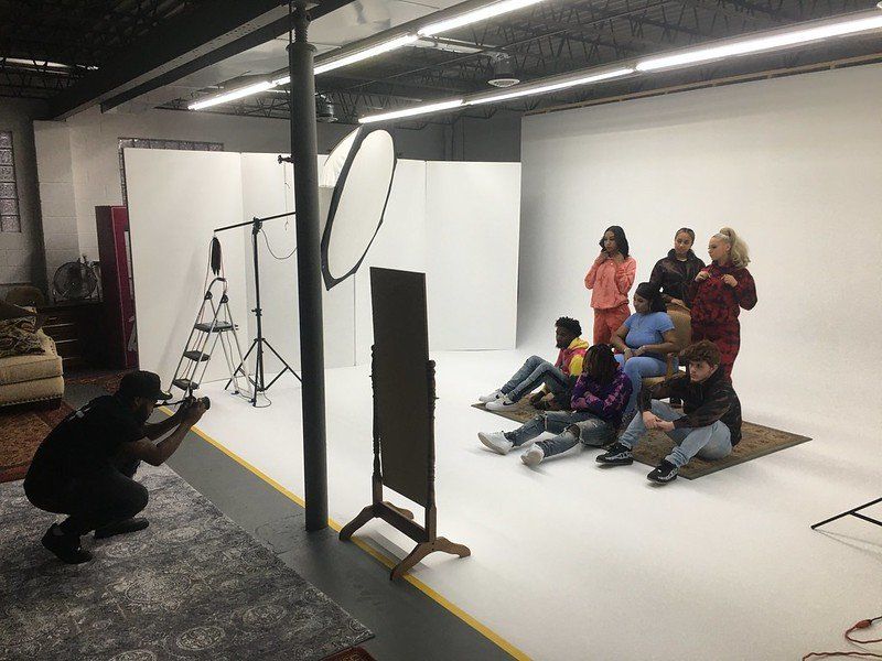 A man is taking a picture of a group of people in a studio.