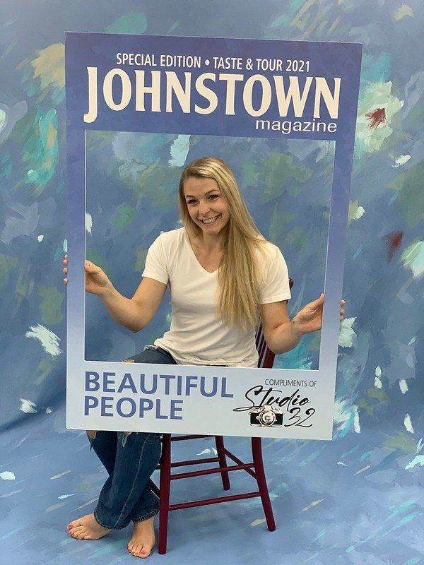 A woman is sitting in a chair holding a johnstown magazine frame.