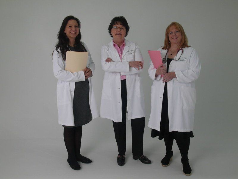 Three women in white coats are posing for a picture