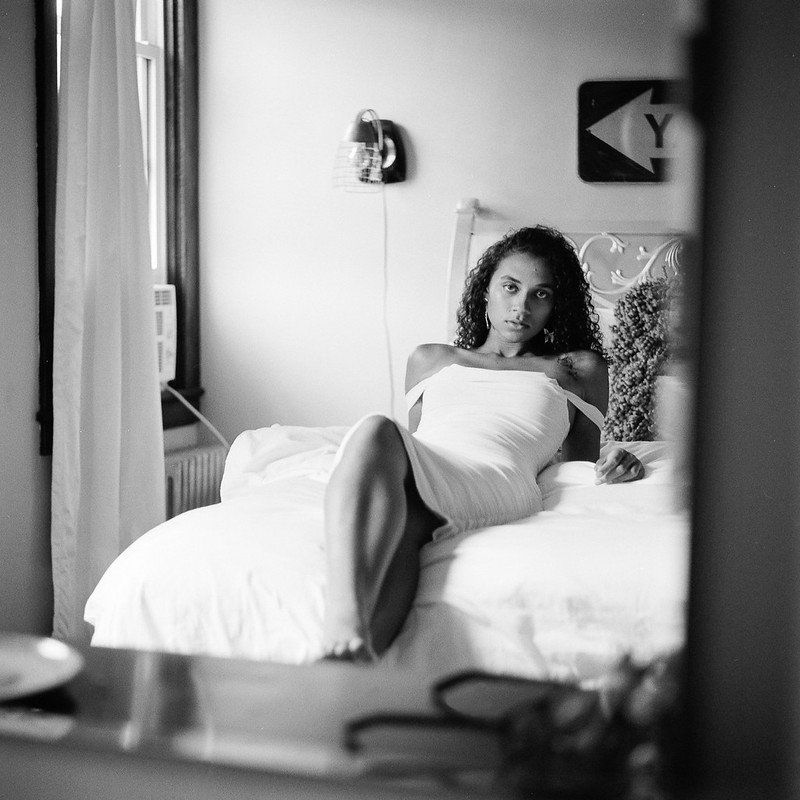 A black and white photo of a woman sitting on a bed