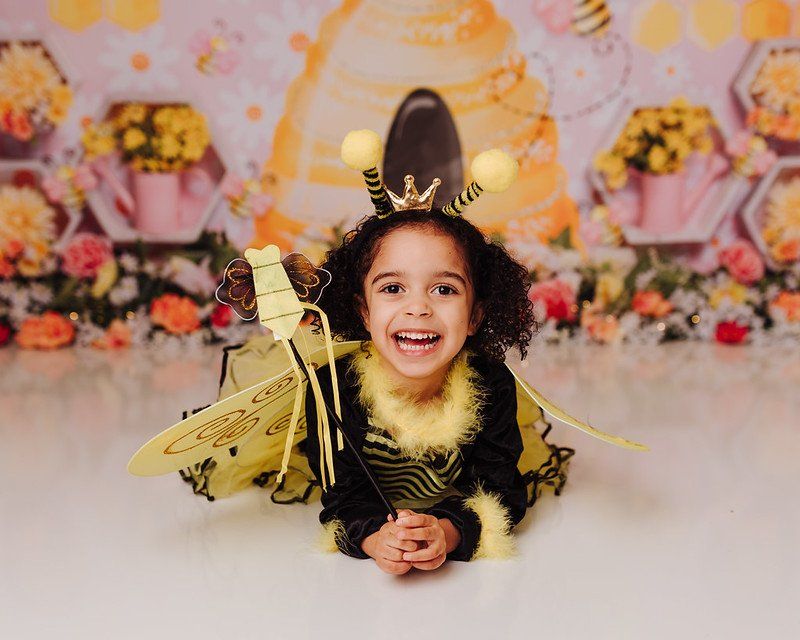 A little girl in a bee costume is laying on the floor.