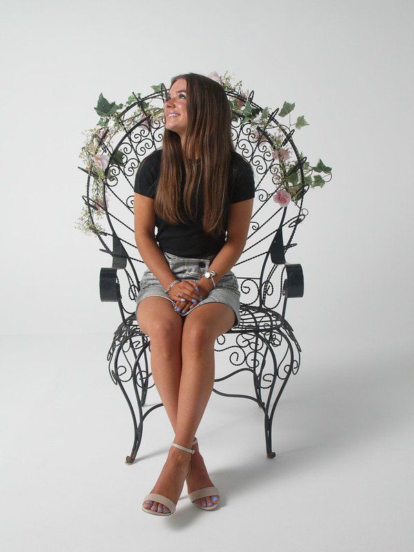 A woman is sitting in a chair with flowers on it