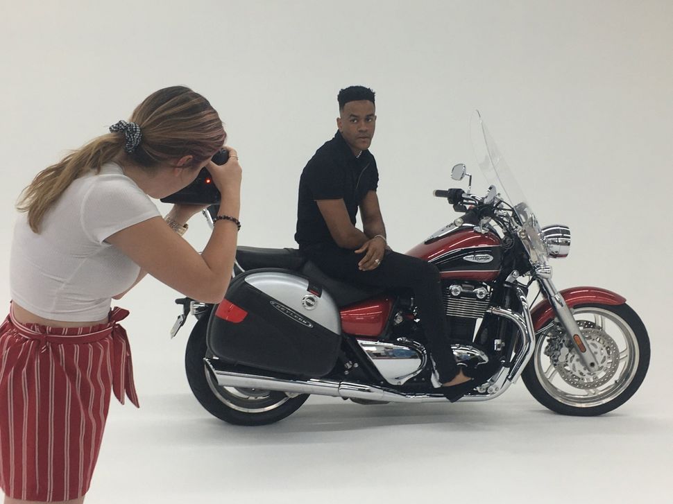 A woman is taking a picture of a man on a motorcycle